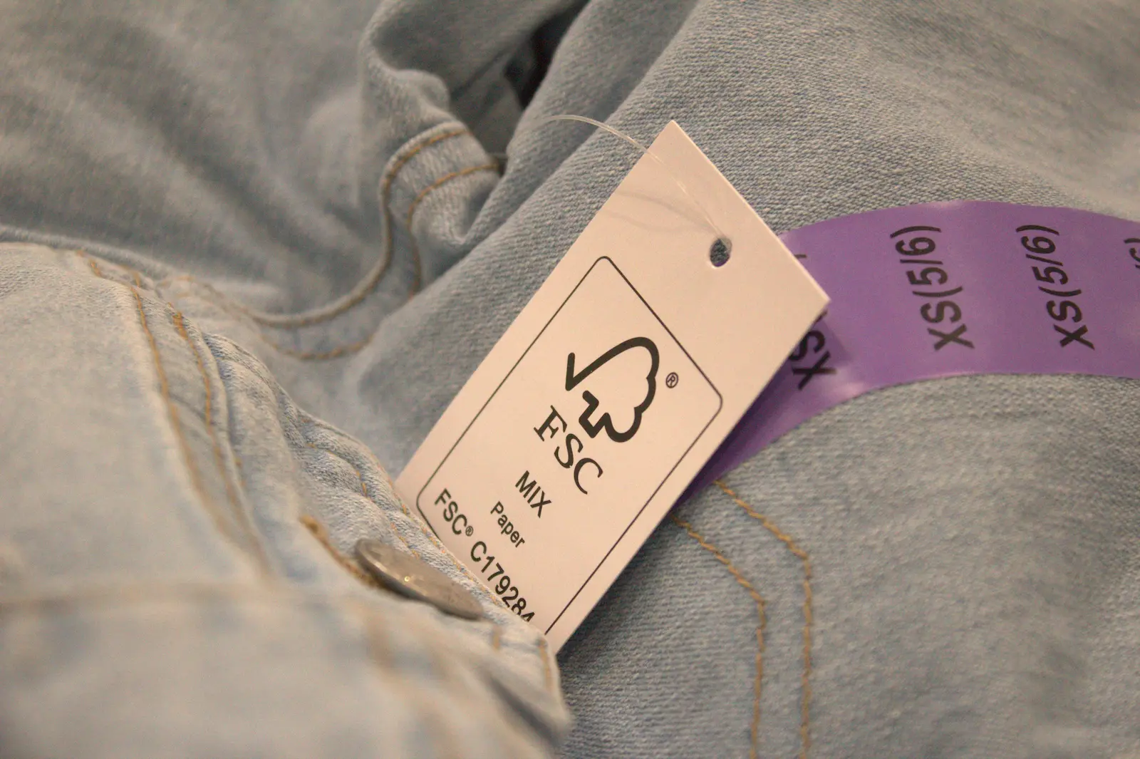 Close-up of an FSC certification tag on a pair of light wash jeans.